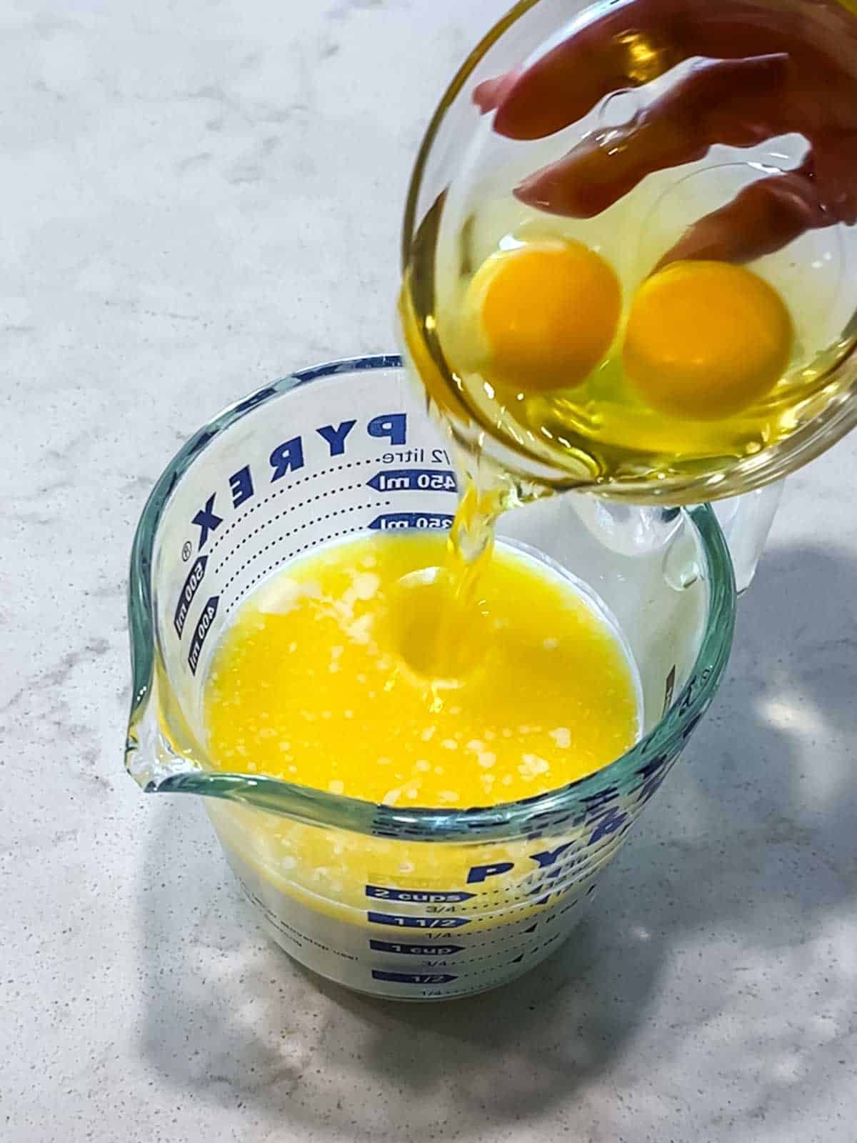 Adding eggs to the buttermilk and butter in a measuring cup.