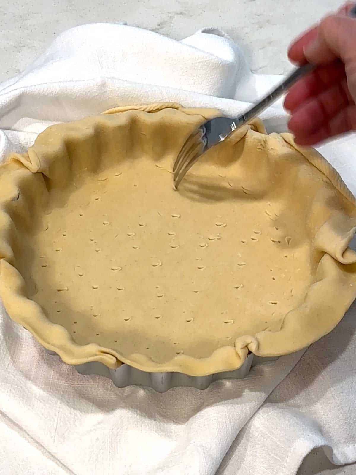 Piercing the botton of the pastry with a fork.