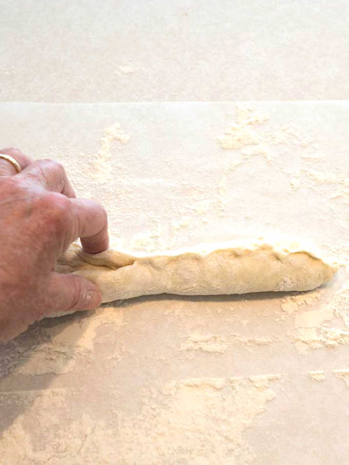 Pinching the edges the dough to form the French bread.