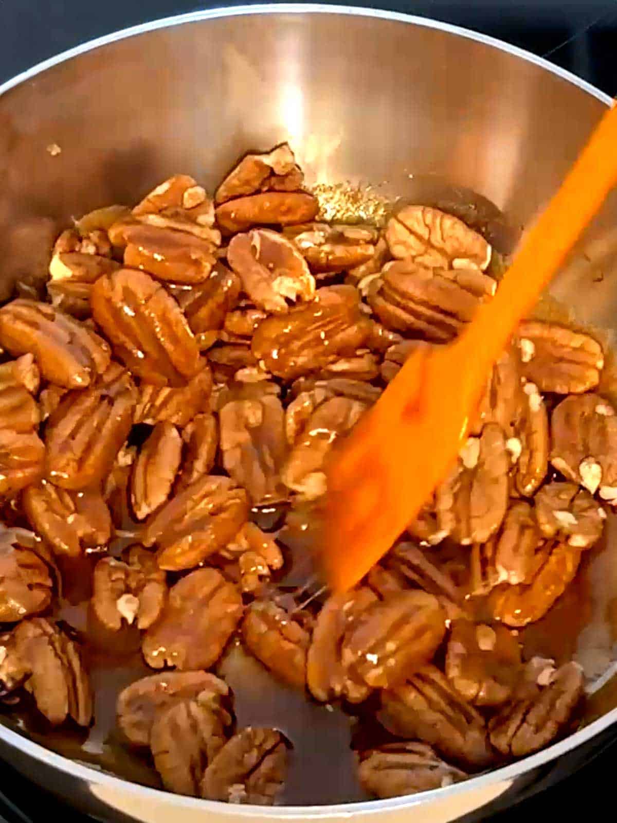 Stirring pecans with sugar mixture in a saucier pan.