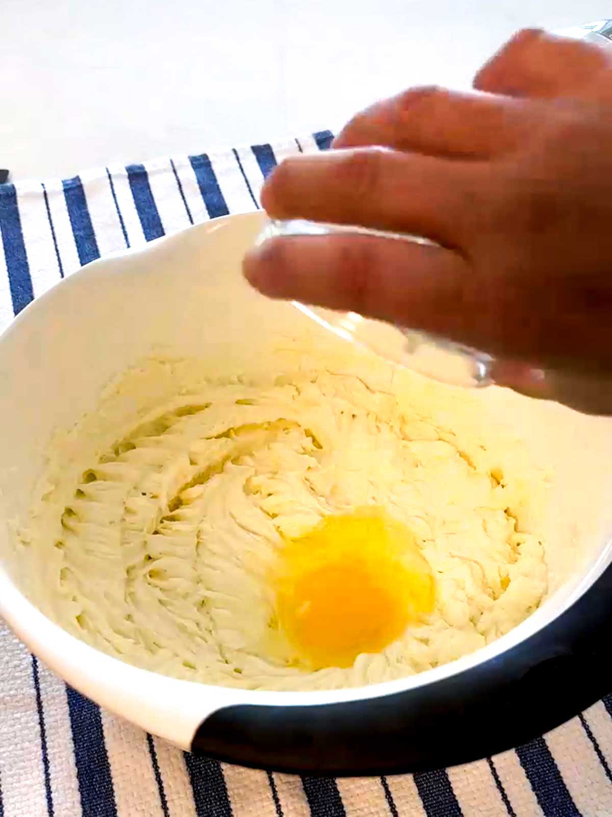 Adding eggs to the pumpkin cheesecake filling.