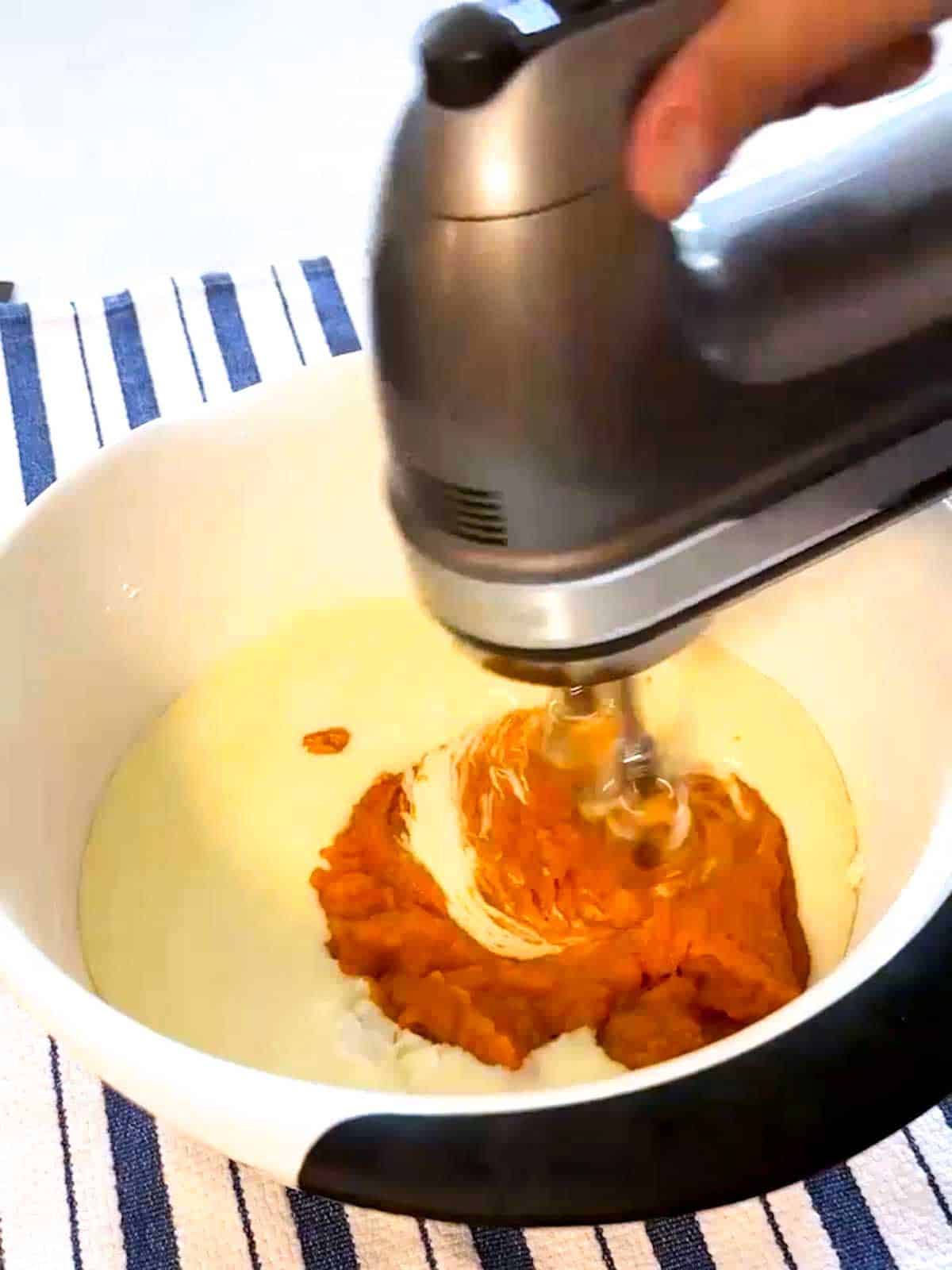 Adding pumpkin puree to the cheesecake batter.