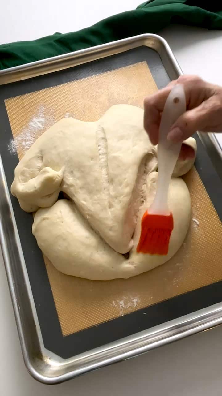 Brushing the turkey bread with an egg wash.