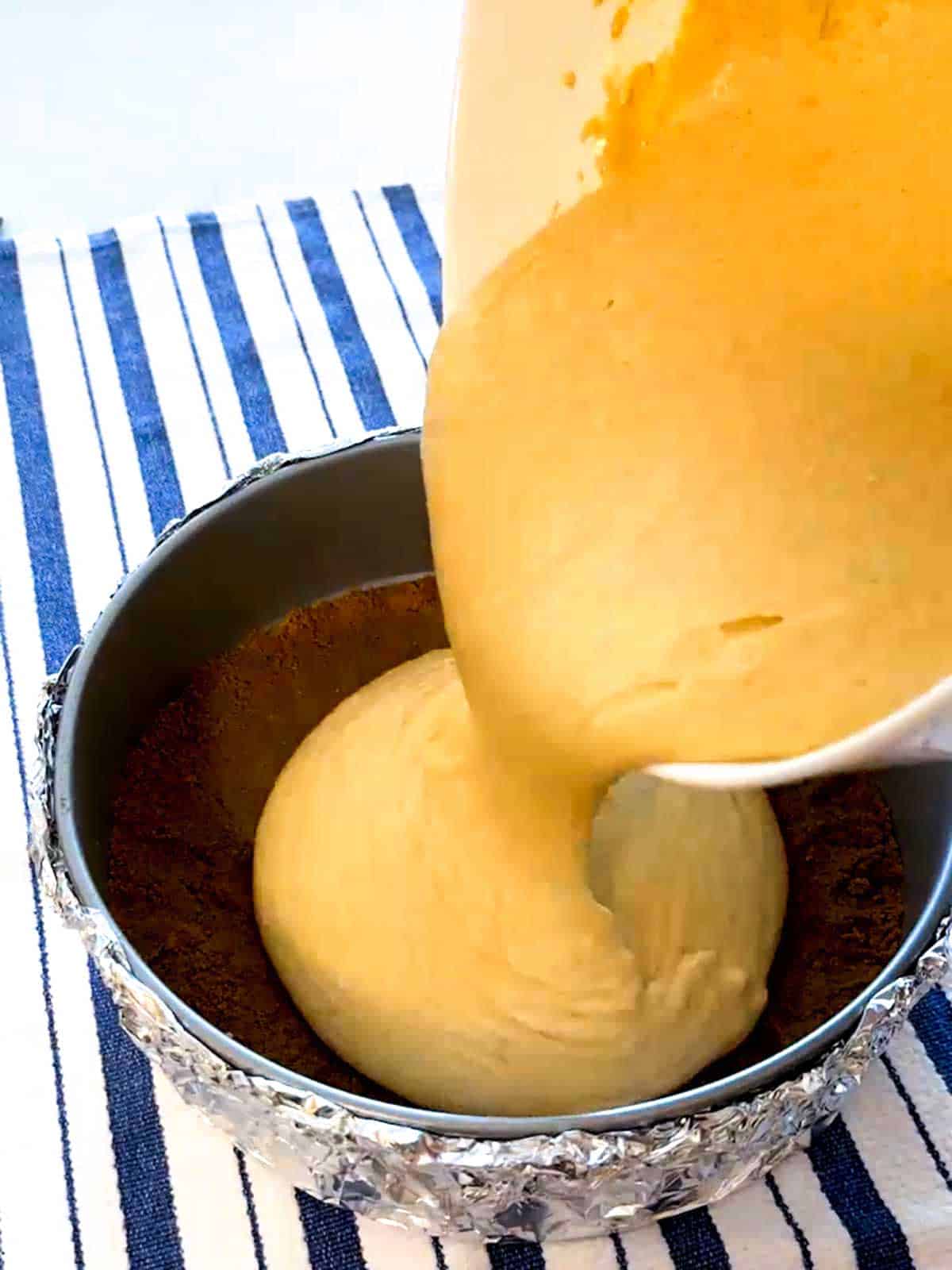 Pouring cheesecake filling into the springform pan.