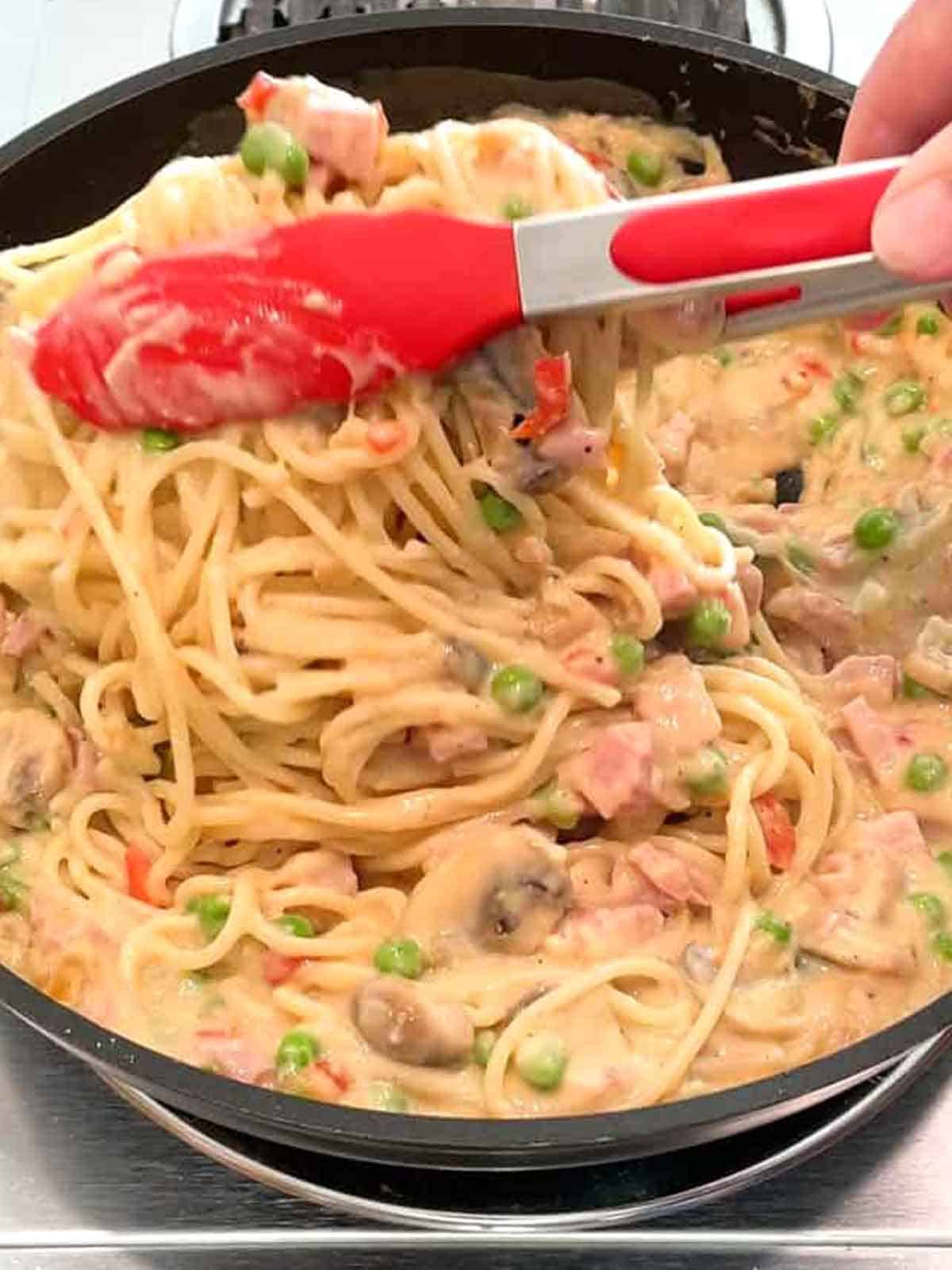 Adding cooked spaghetti to the tetrazzini sauce.
