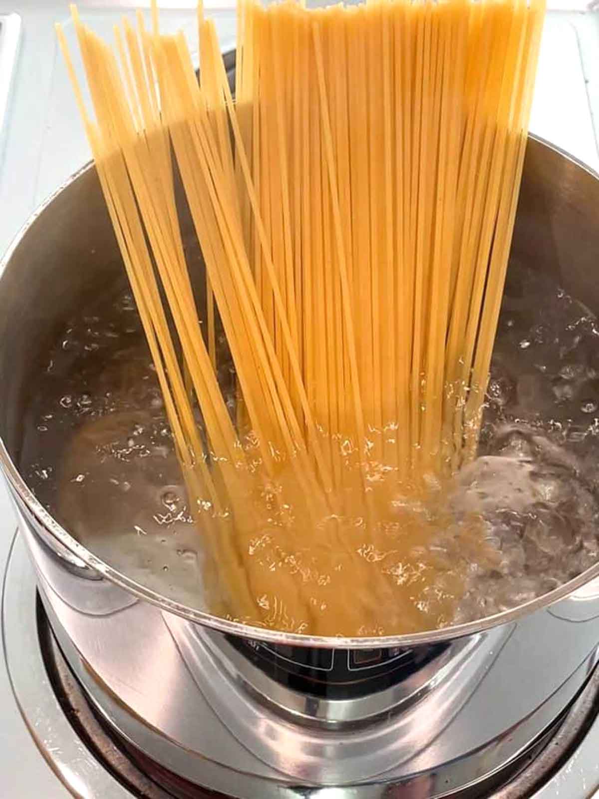Cooking spaghettin in a pot of boiling water.
