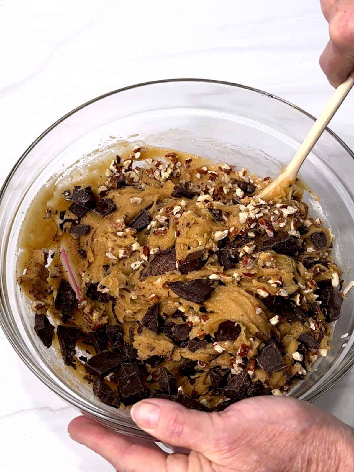 Stirring chopped chocolate and toasted pecans into the cookie dough.