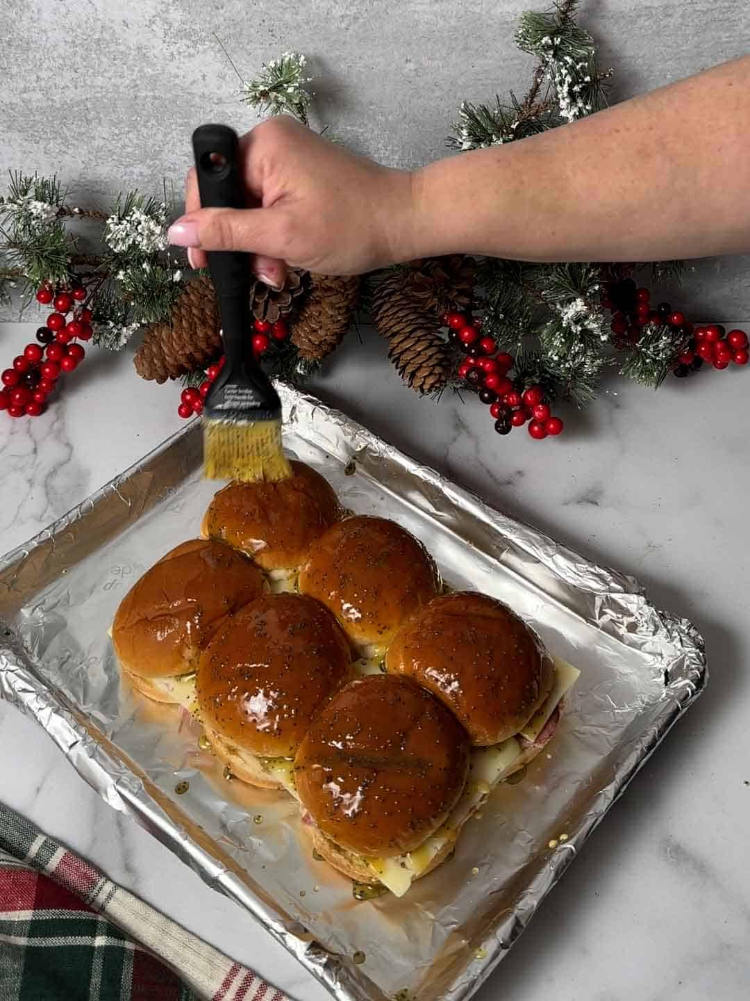 Brushing honey-butter glaze on top of the sliders