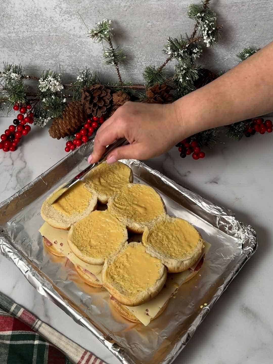 Spreading honey mustard  on the top slider buns