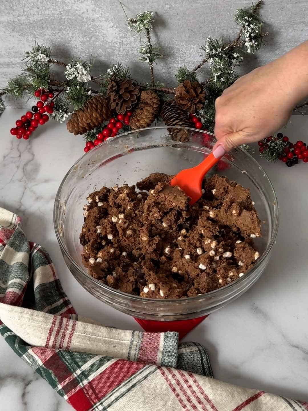 Stirring chocolate chips and marshmallows into the cookie dough