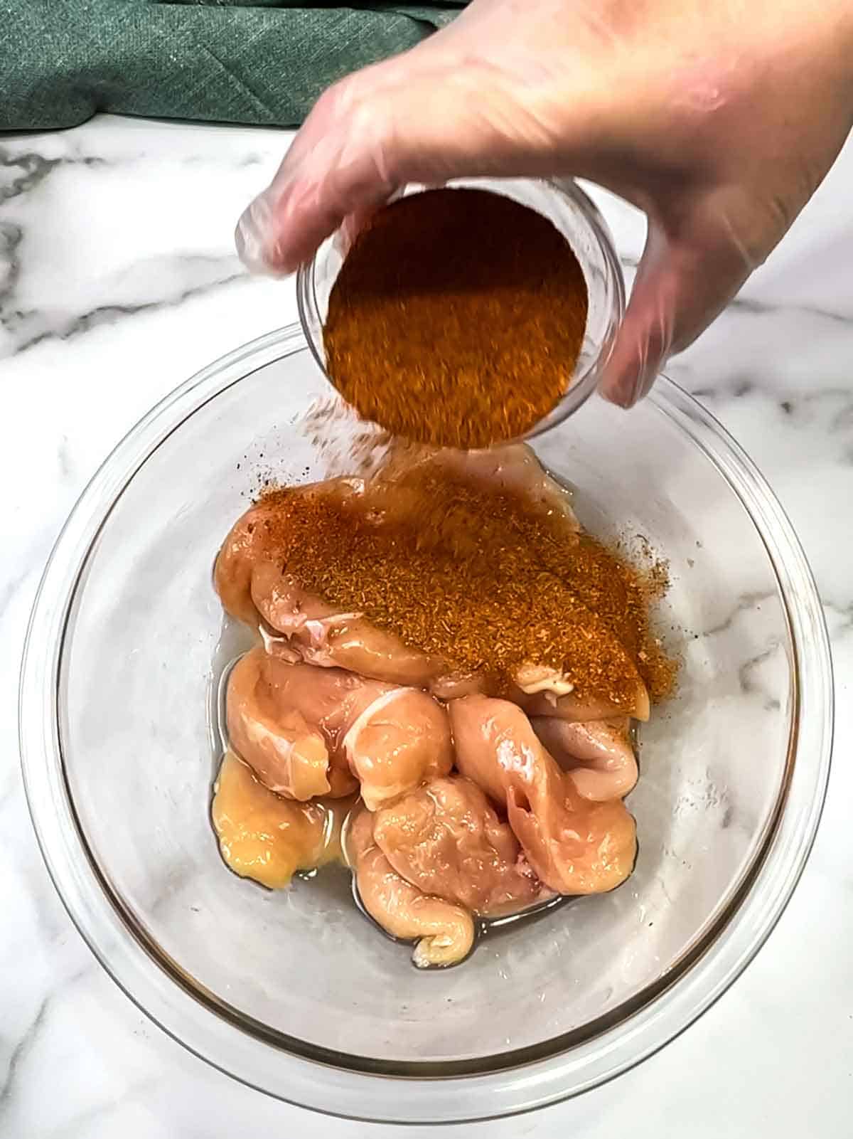 adding cajun seasoning blend to chicken and oil