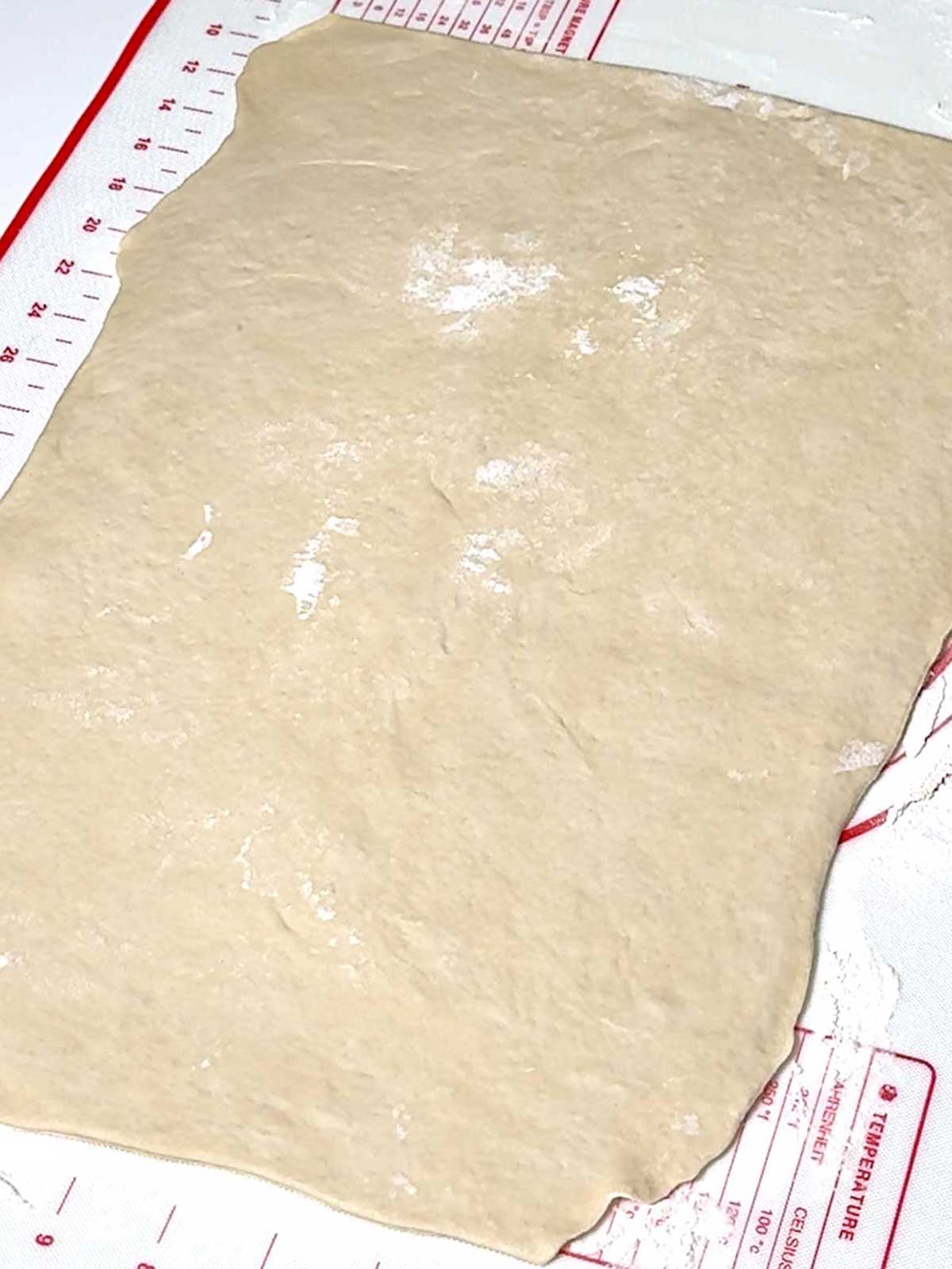 Pizza dough rolled into a 16 by 10 inch rectangle.