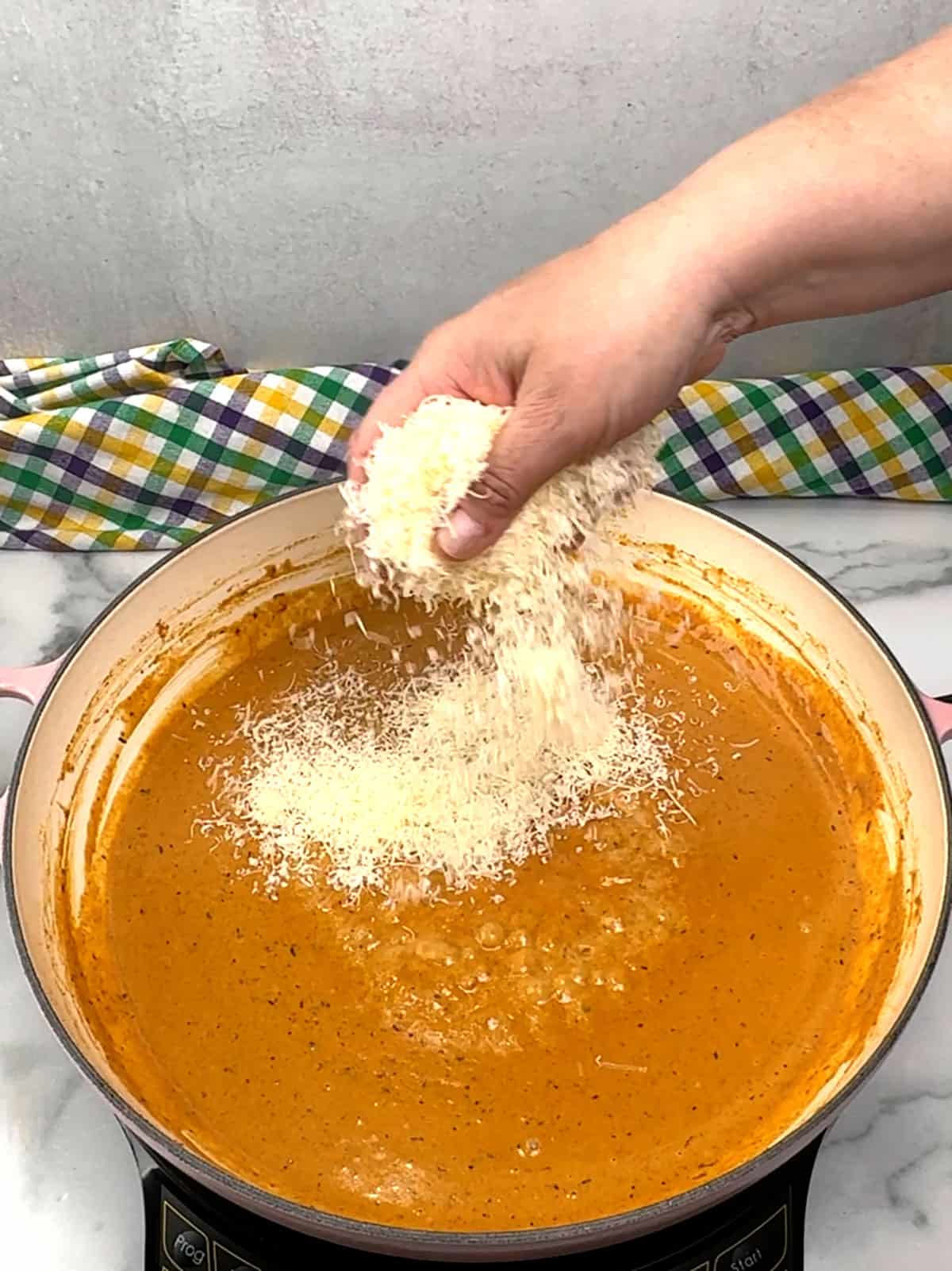 adding grated parmesan cheese to sauce