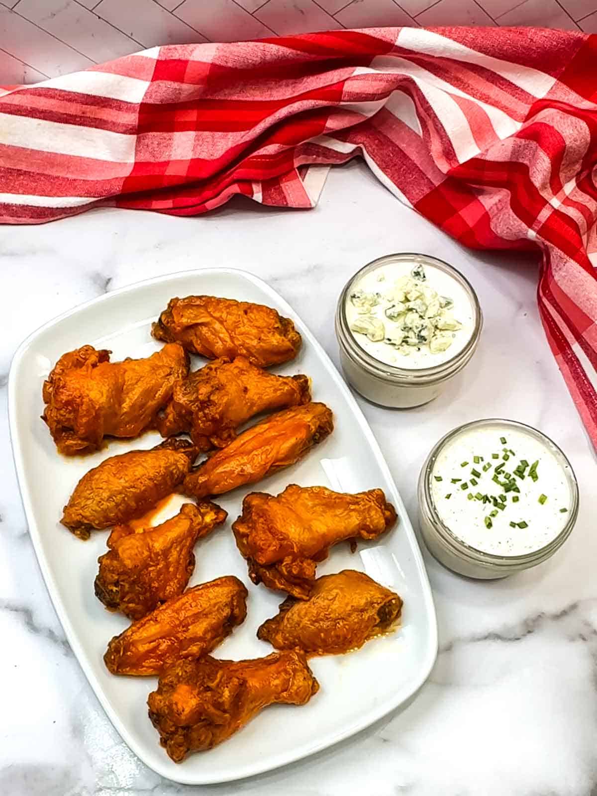 wings on a plate with blue cheese and ranch on the side