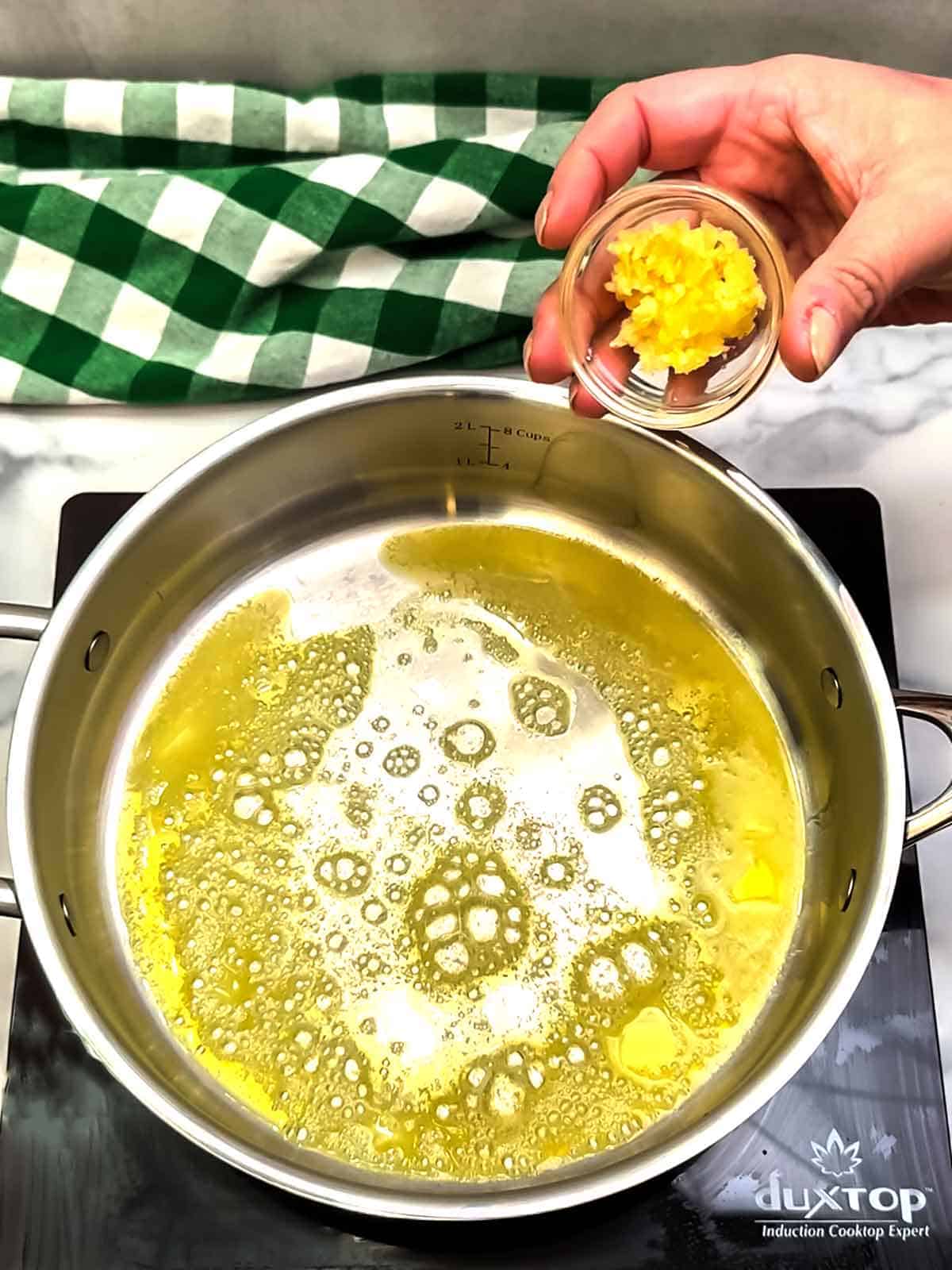 adding minced garlic to melted butter