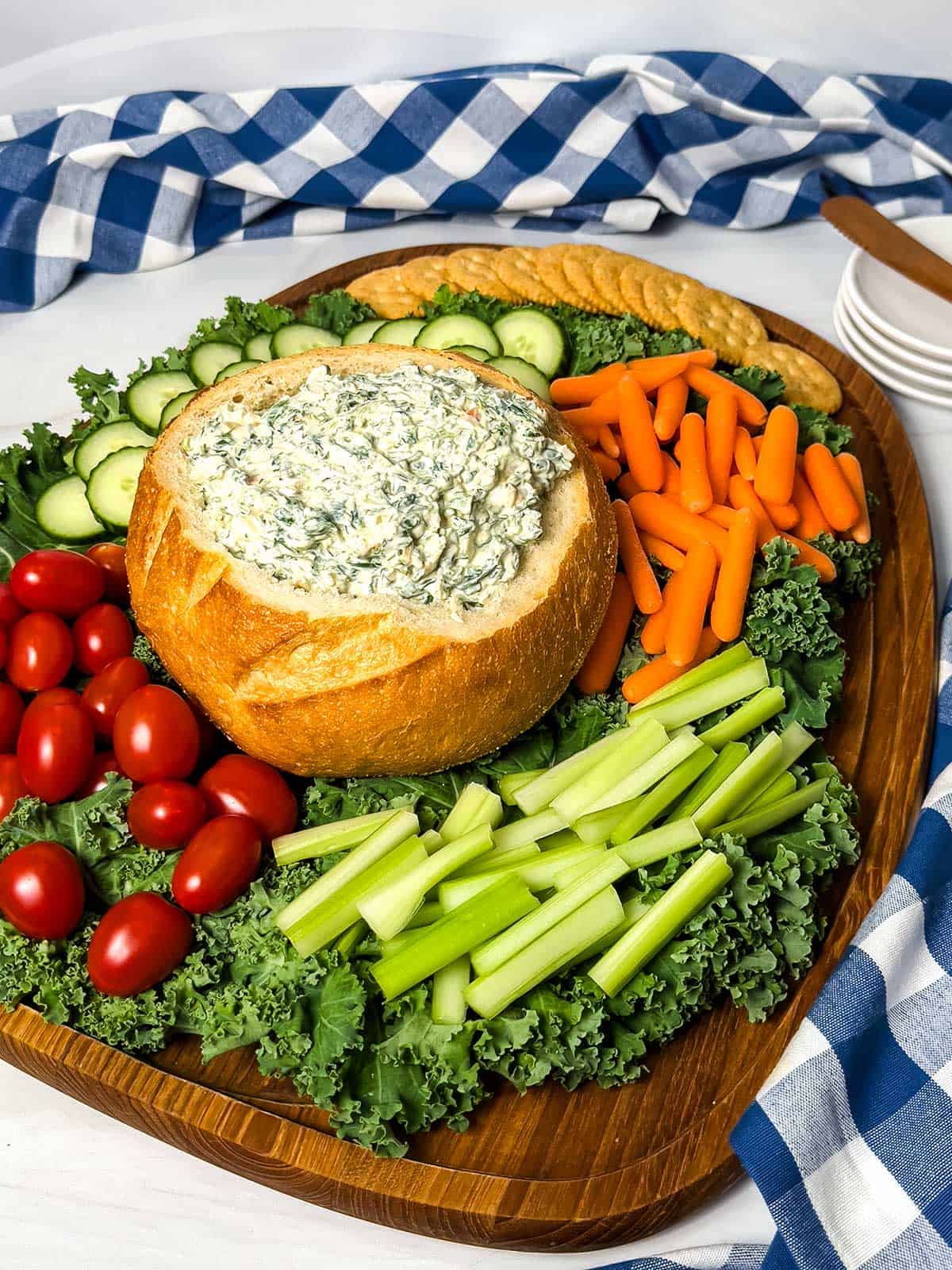 Cold spinach dip in a bread bowl surrounded by veggies.