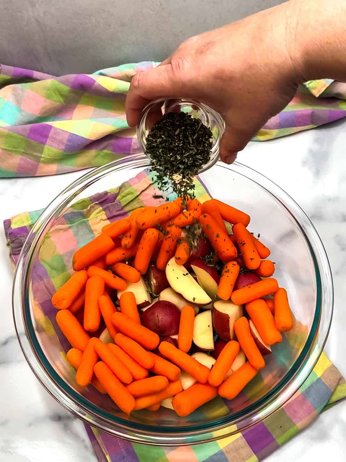 adding rosemary and thyme to the potatoes and carrots