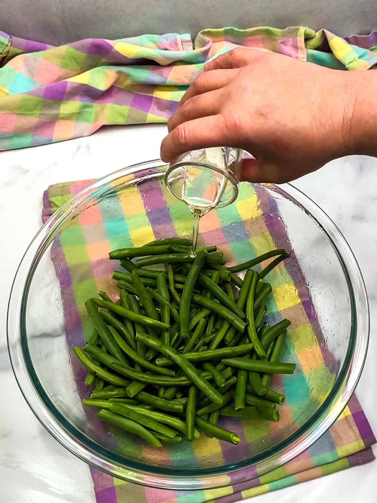 adding oil to green beans