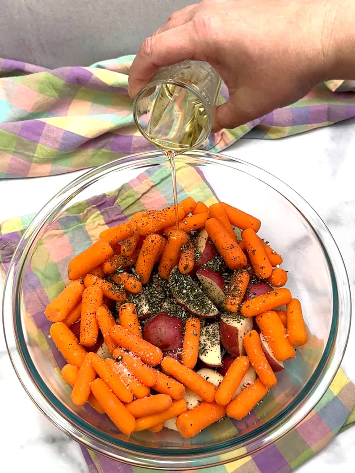 adding herbs, spices, and oil to potatoes and carrots