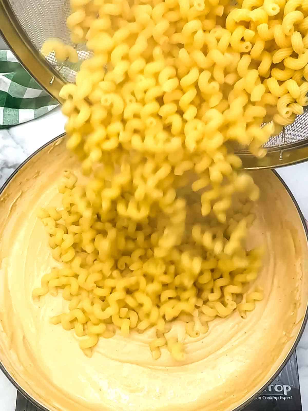 adding pasta to sauce