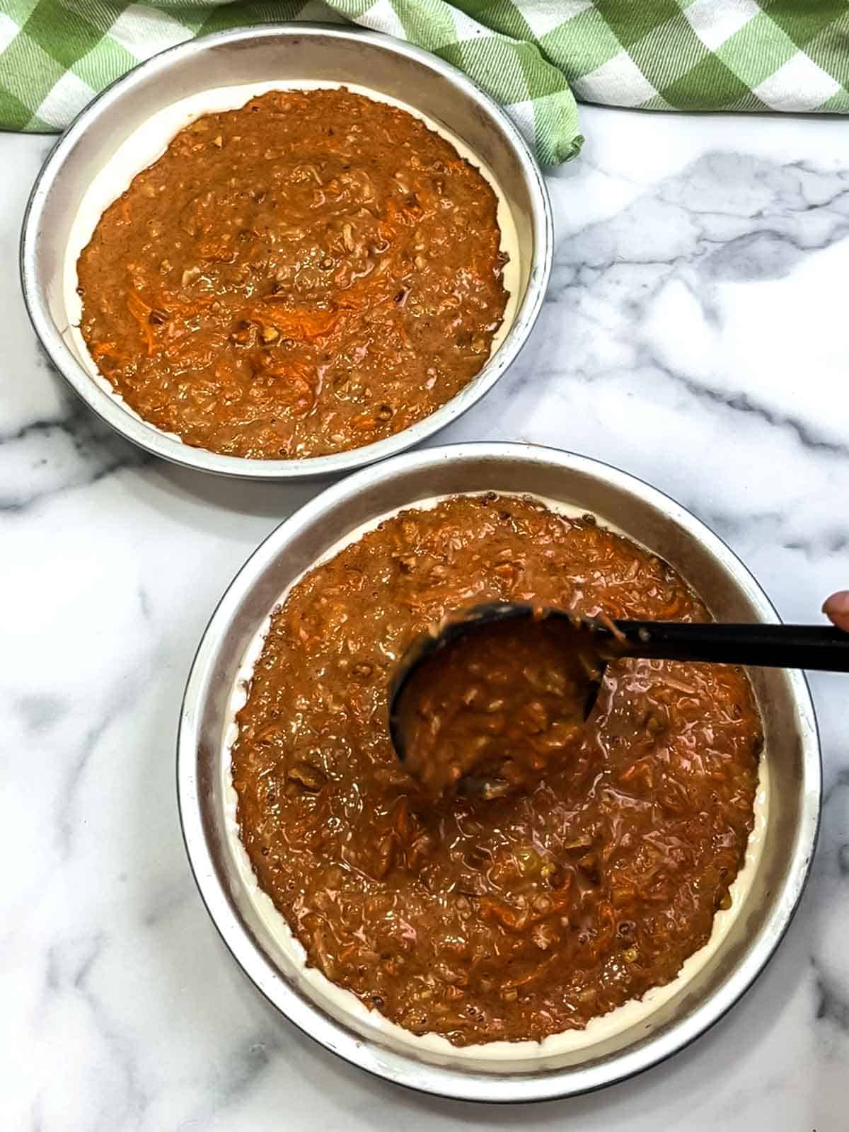 filling greased and floured pans with the carrot cake batter