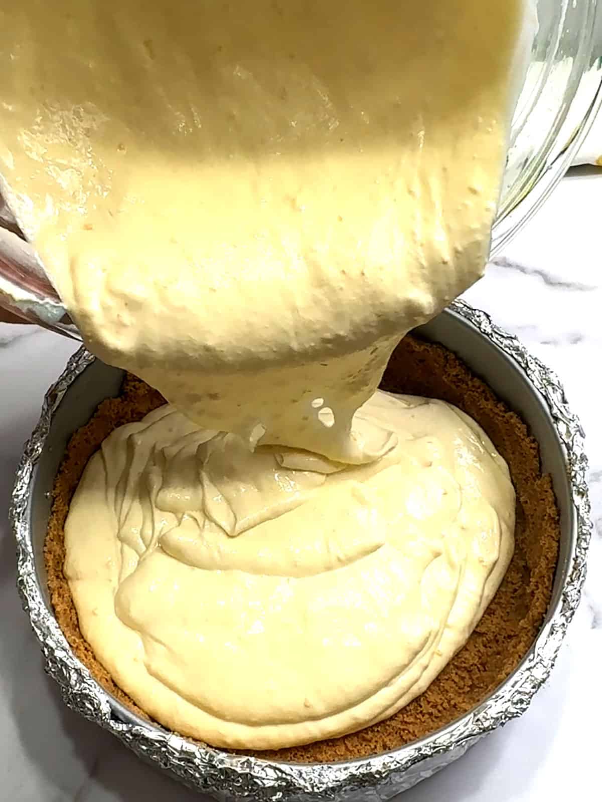 pouring cheesecake filling into prepared pan
