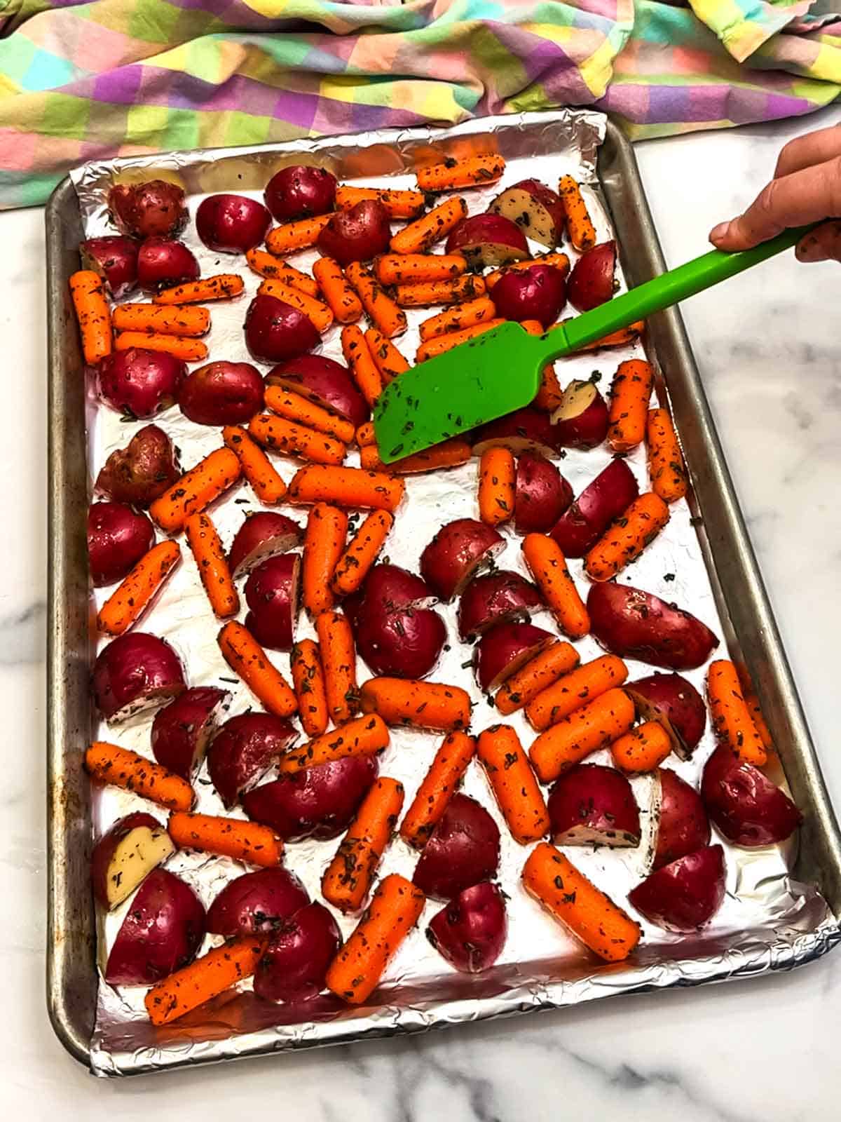 spreading potatoes and carrots on the sheet pan