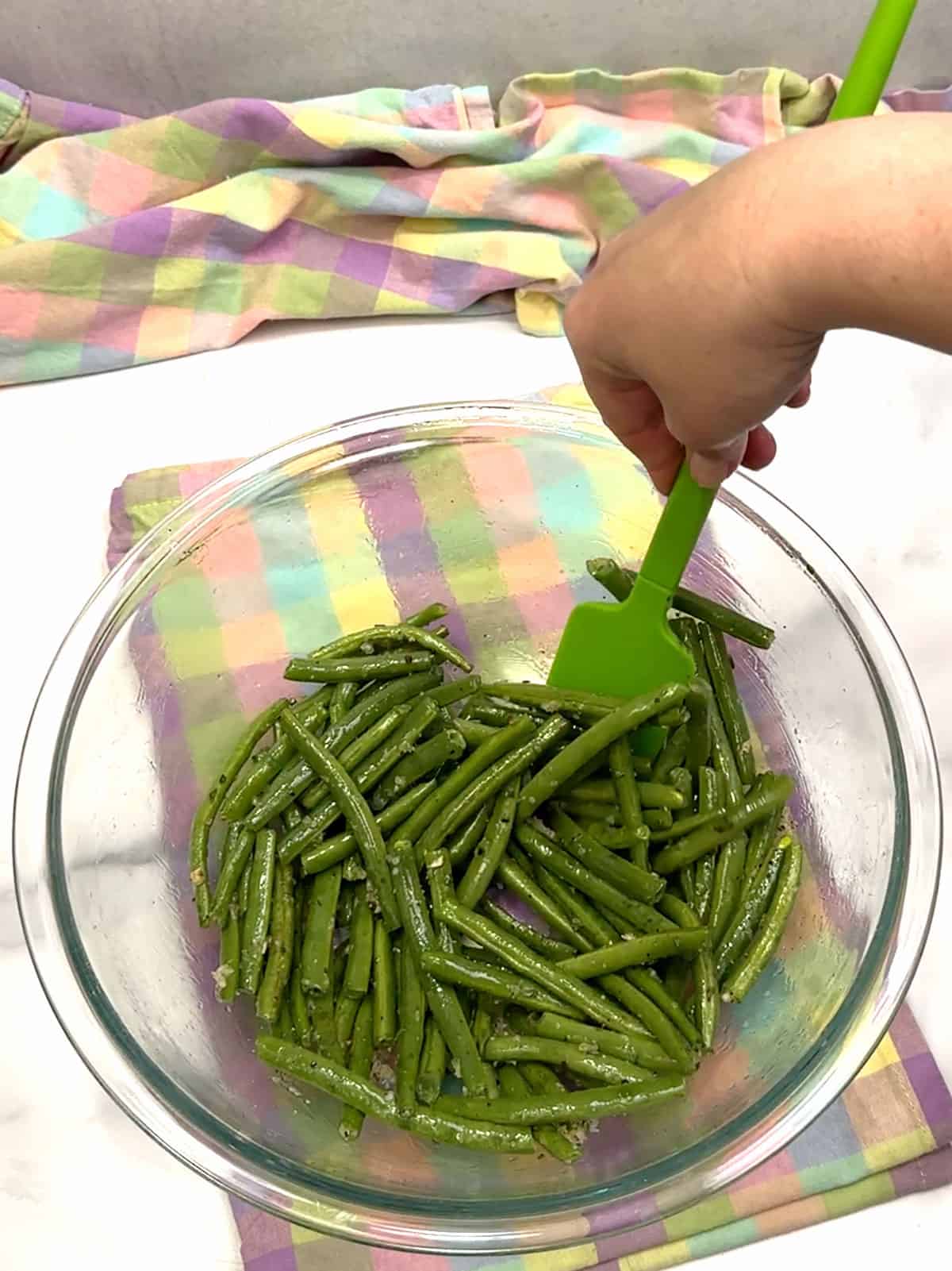 stirring gren beans to coat with garlic, herbs, and oil