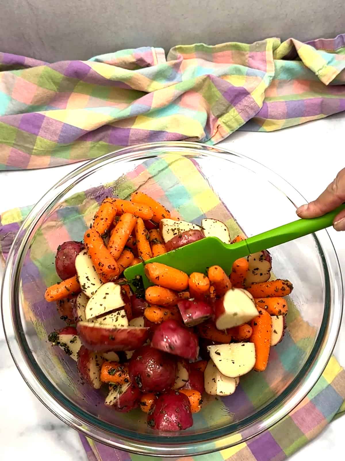 stirring potatoes and carrots to coat them with the herbs, spices, and oil