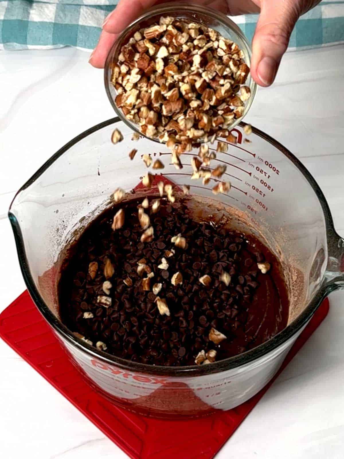 Adding pecan pieces to the mini chocolate chips and the brownie brittle batter.