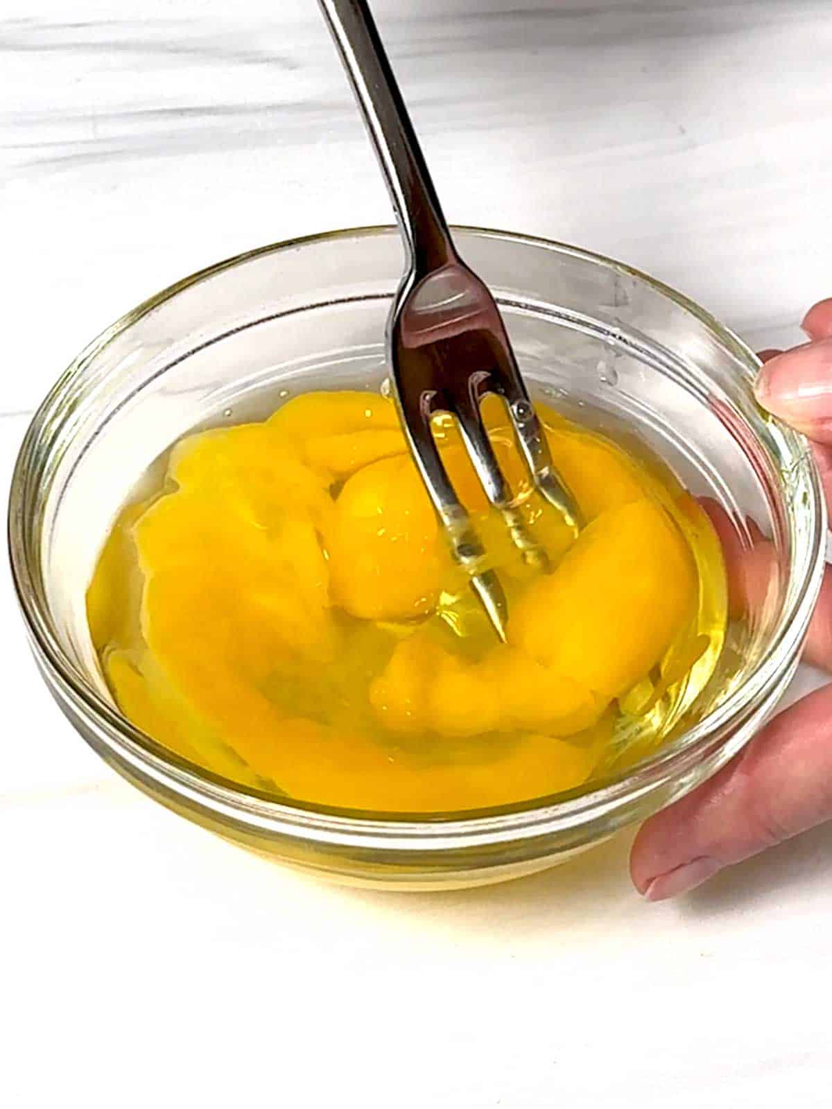 Beating the eggs in a bowl with a fork.