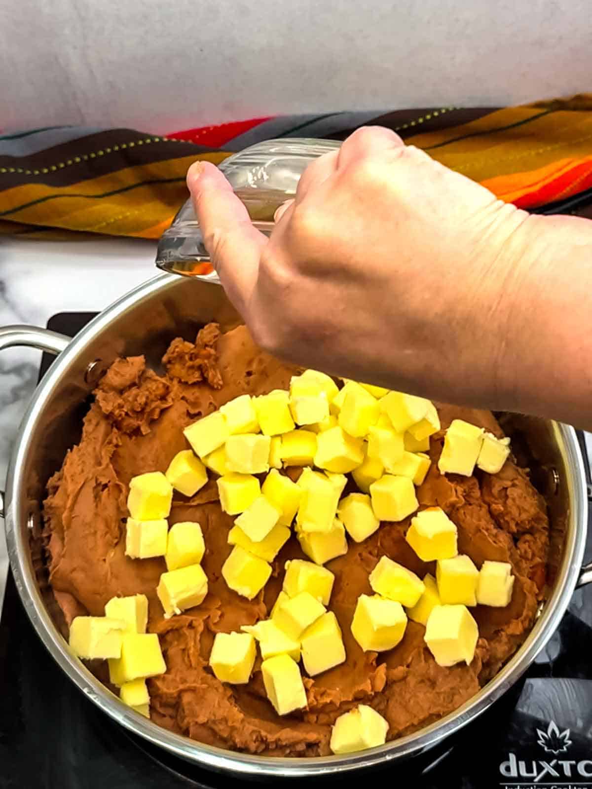 adding refried beans and butter to saucepan