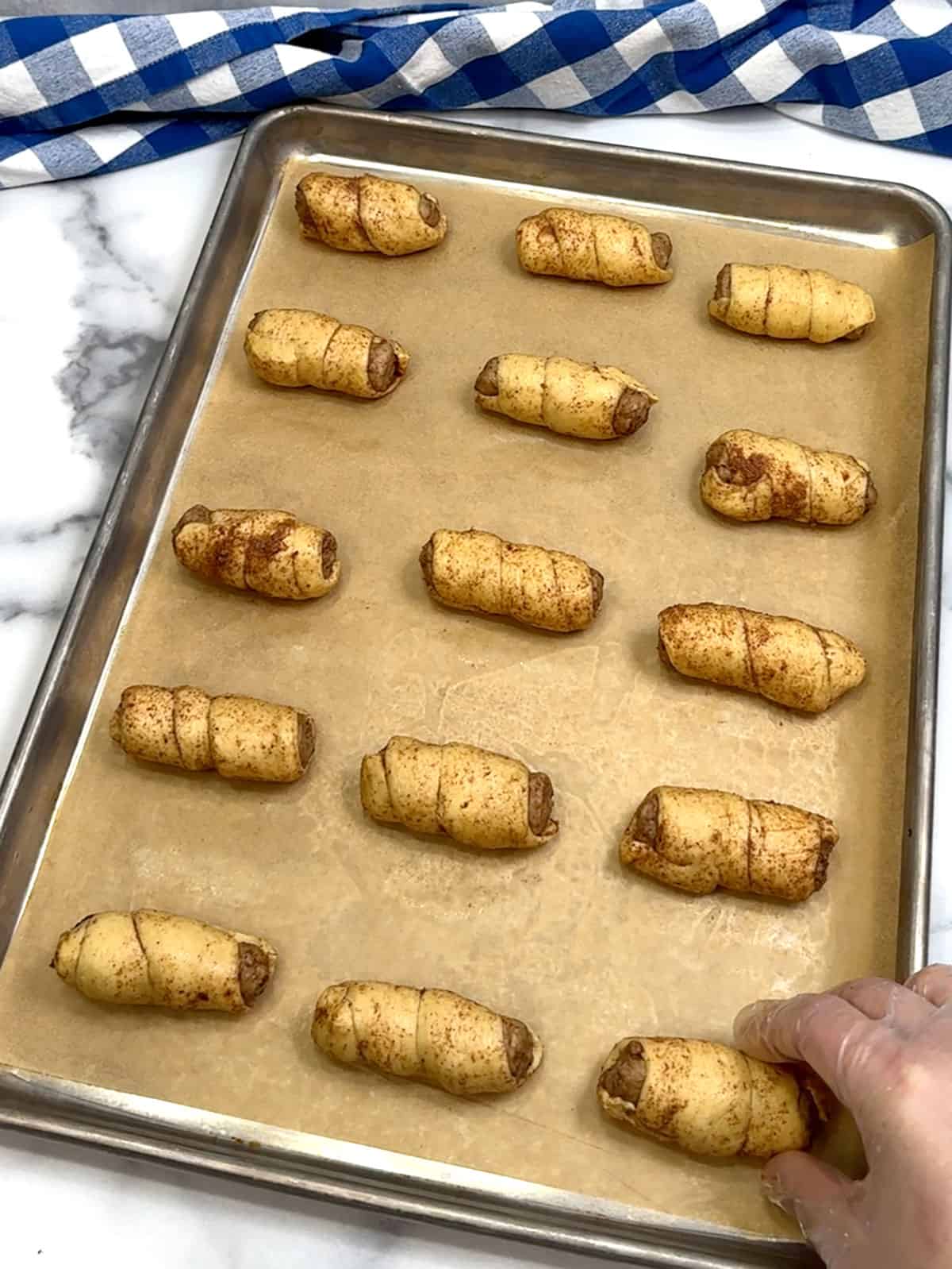 placing wrapped sausages on baking pan