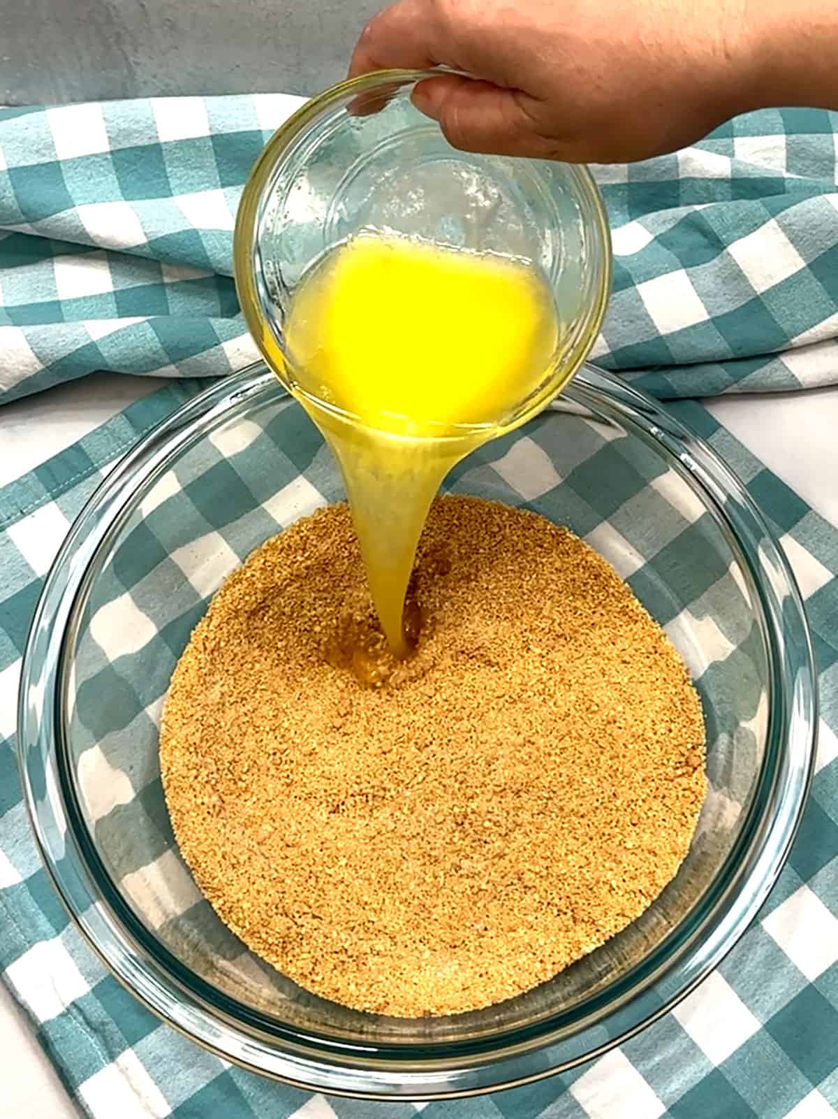 adding melted butter to graham cracker mixture