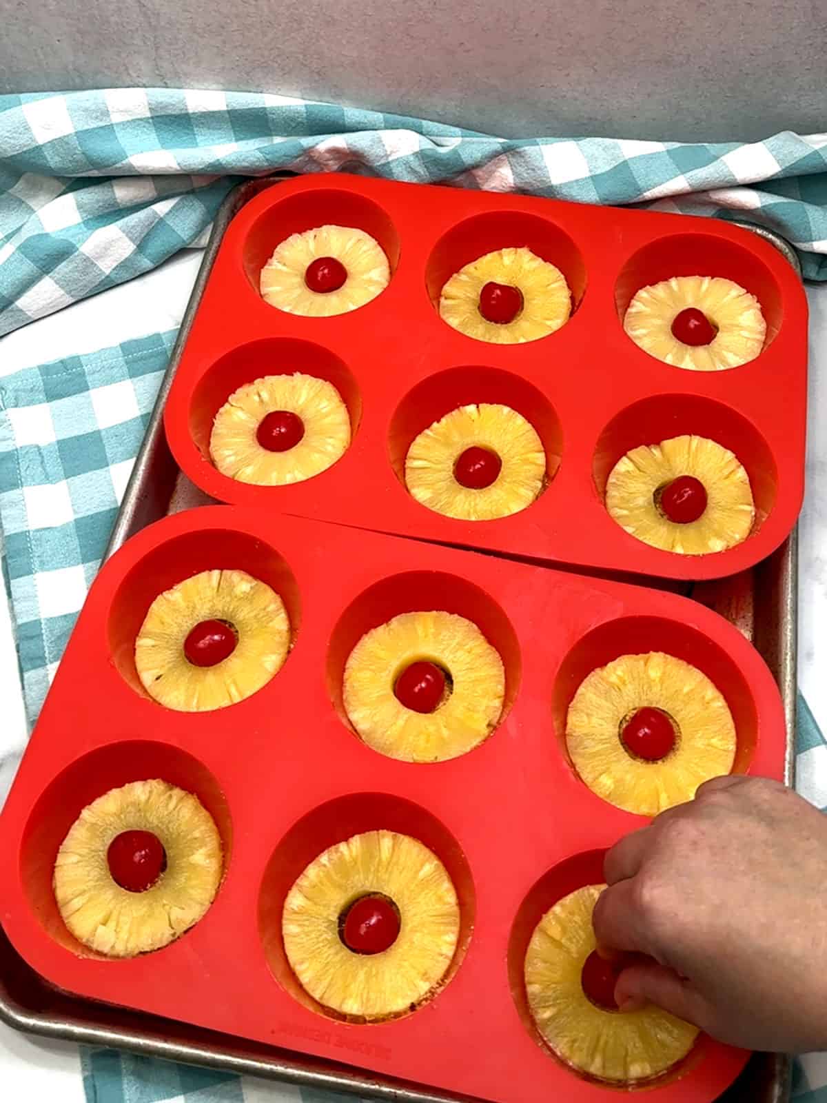 placing cherries inside pineapple rings in prepared pan