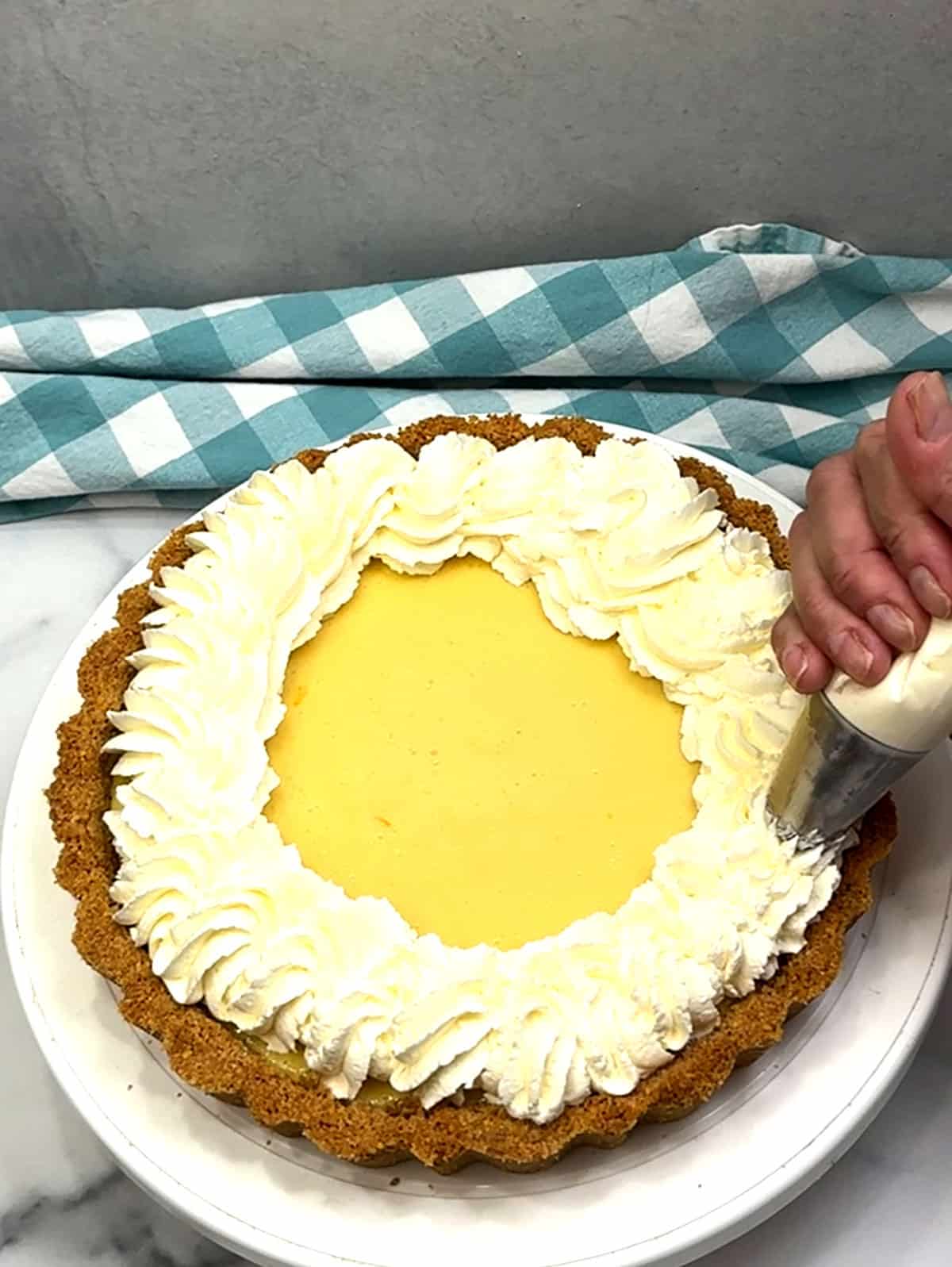 piping whipped cream on top of classic key lime pie