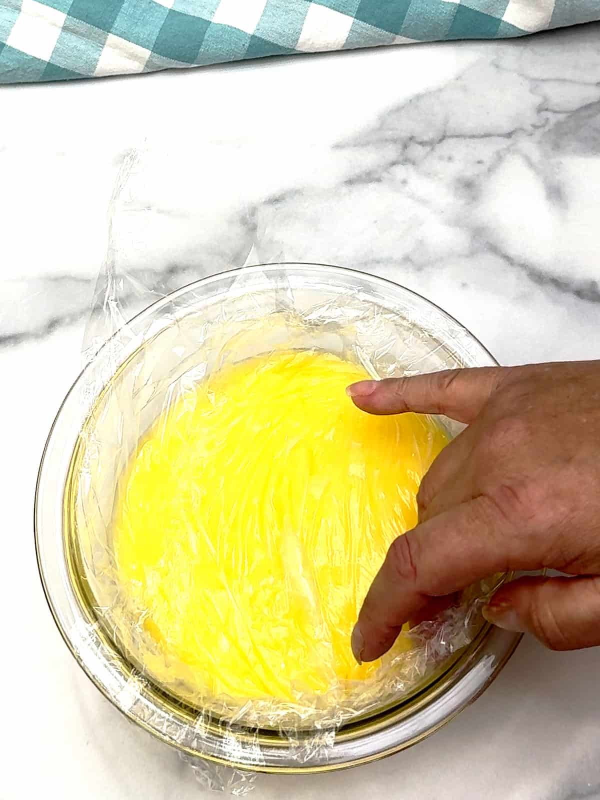 pressing plastic on top of lemon curd