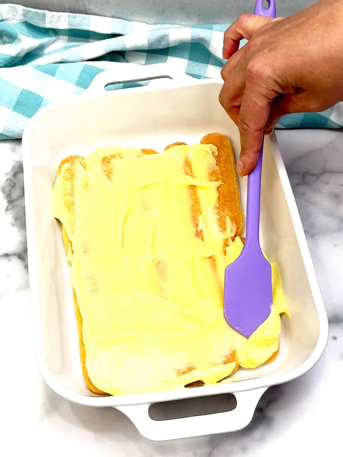 spreading bottom layer of lemon curd over ladyfingers