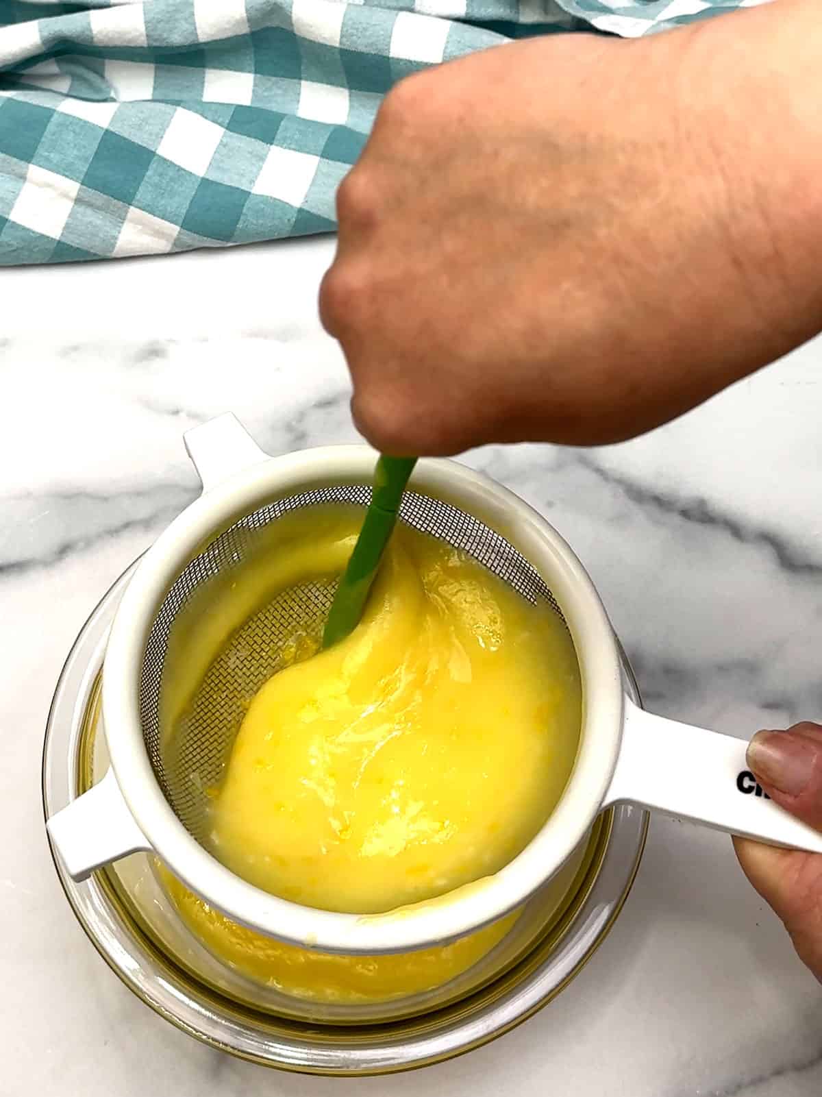 stirring lemon curd into strainer