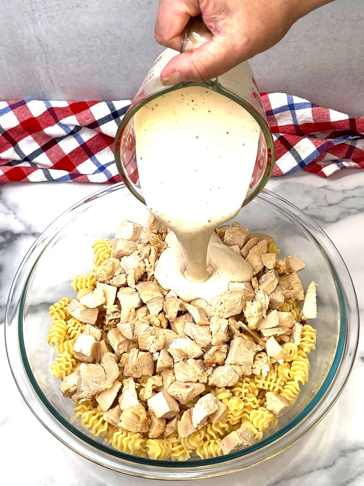 adding caesar dressing to cooked pasta and chicken