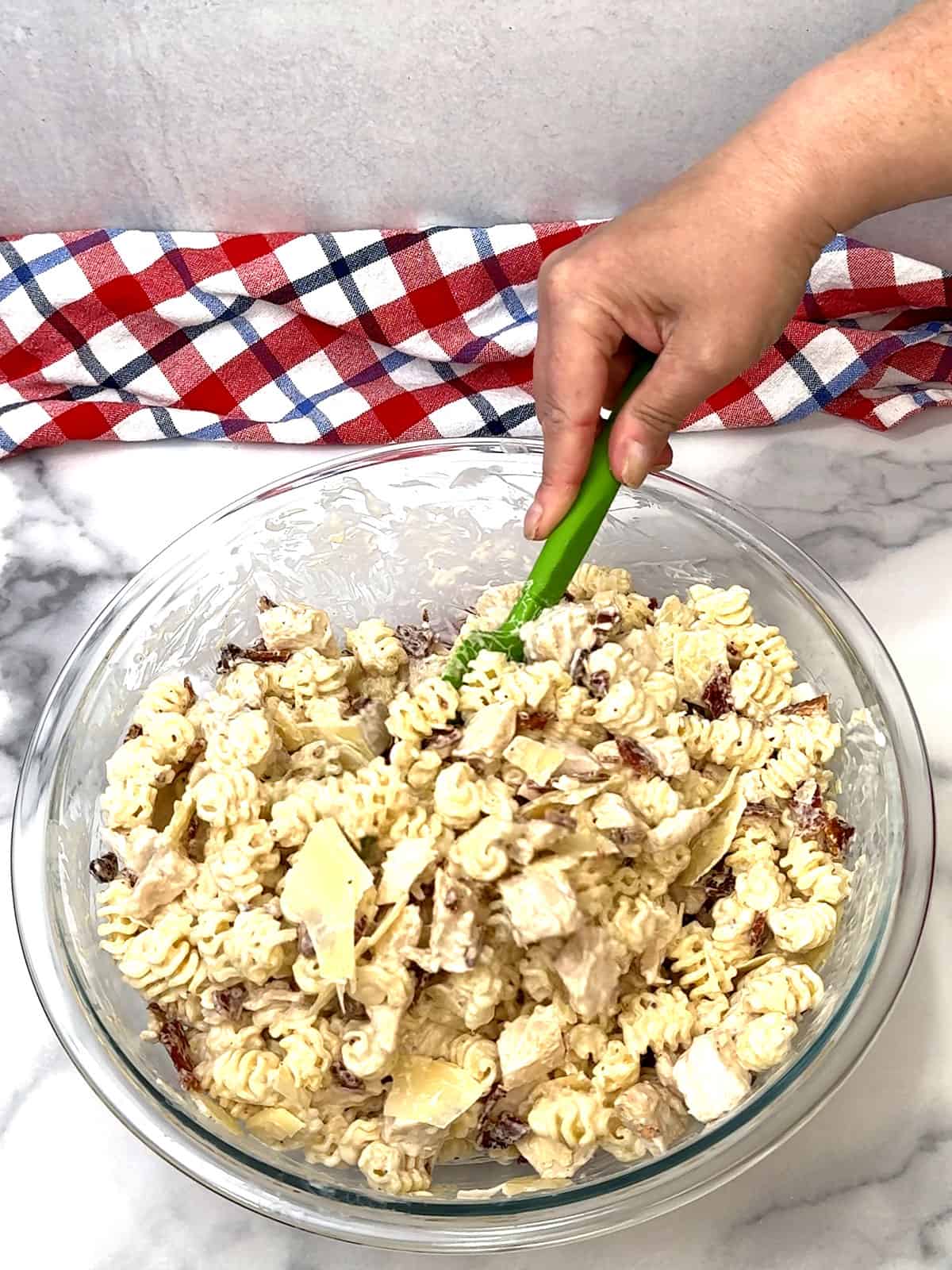 stirring bacon and parmesan into pasta salad