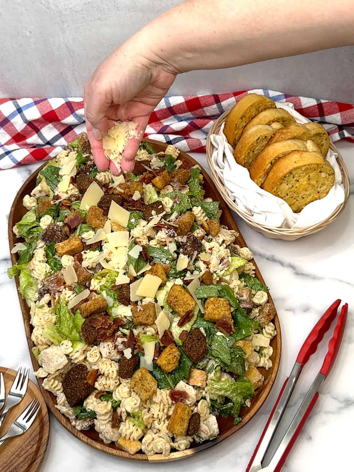topping chicken caesar pasta salad with shaved parmesan cheese