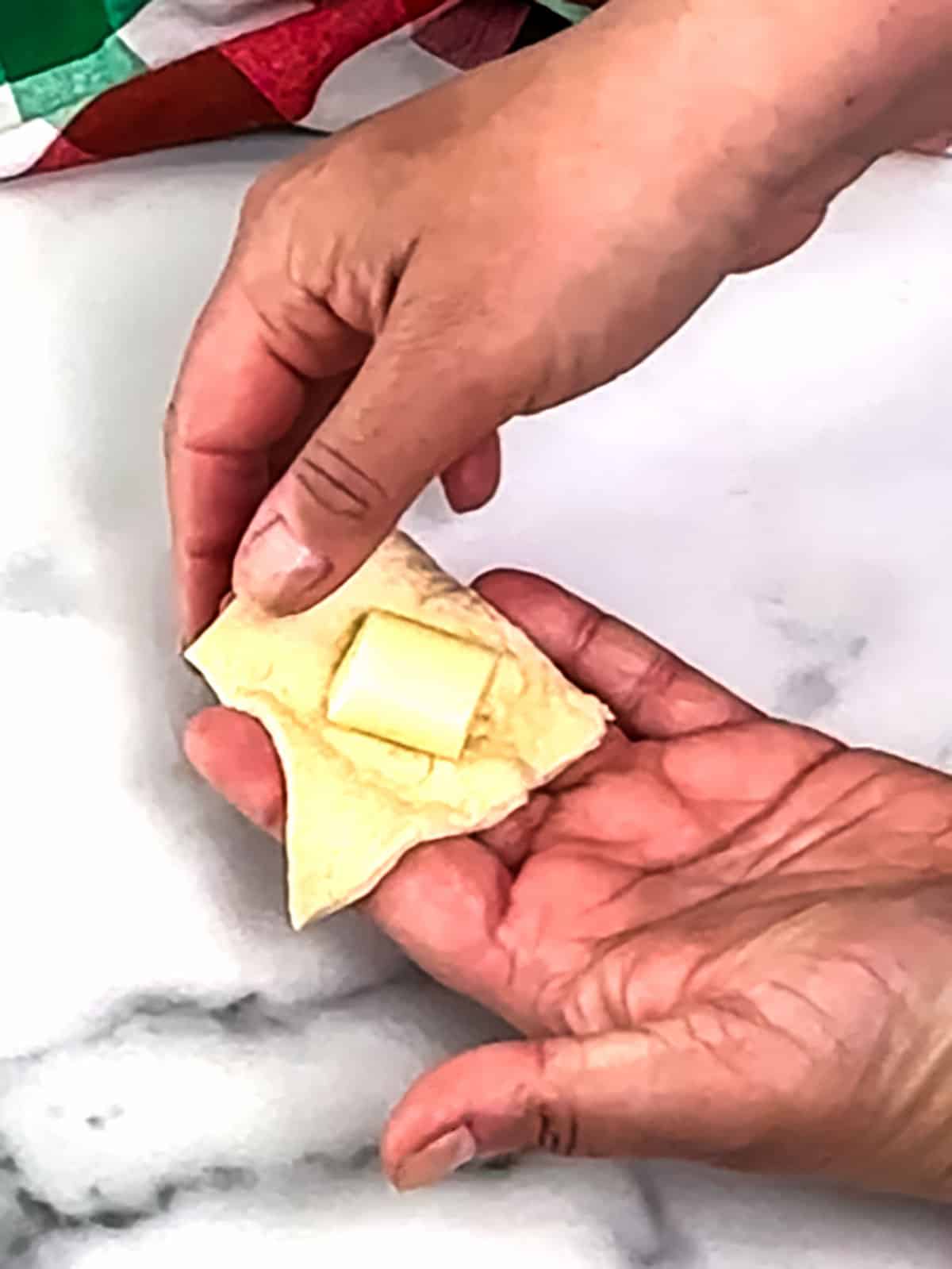 placing cheese [pieces on dough square