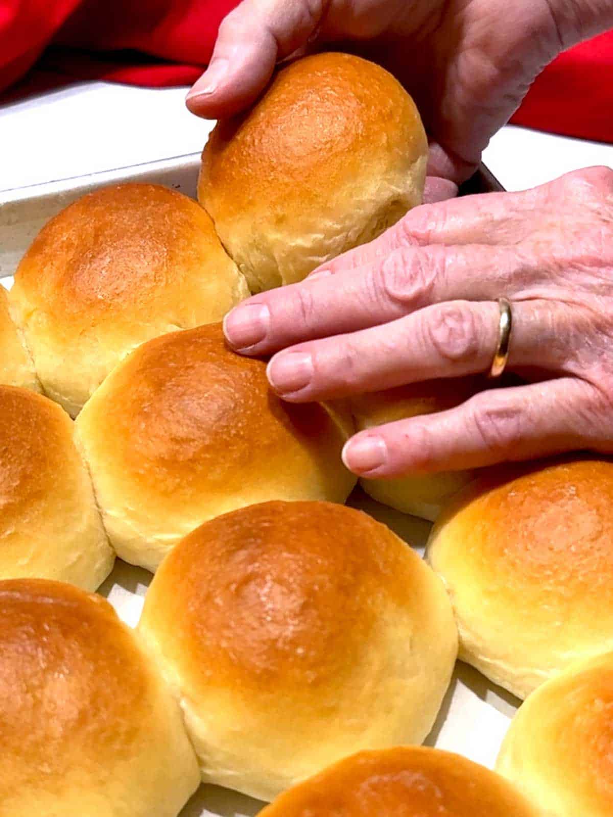 Lifting a dinner roll from the pan.