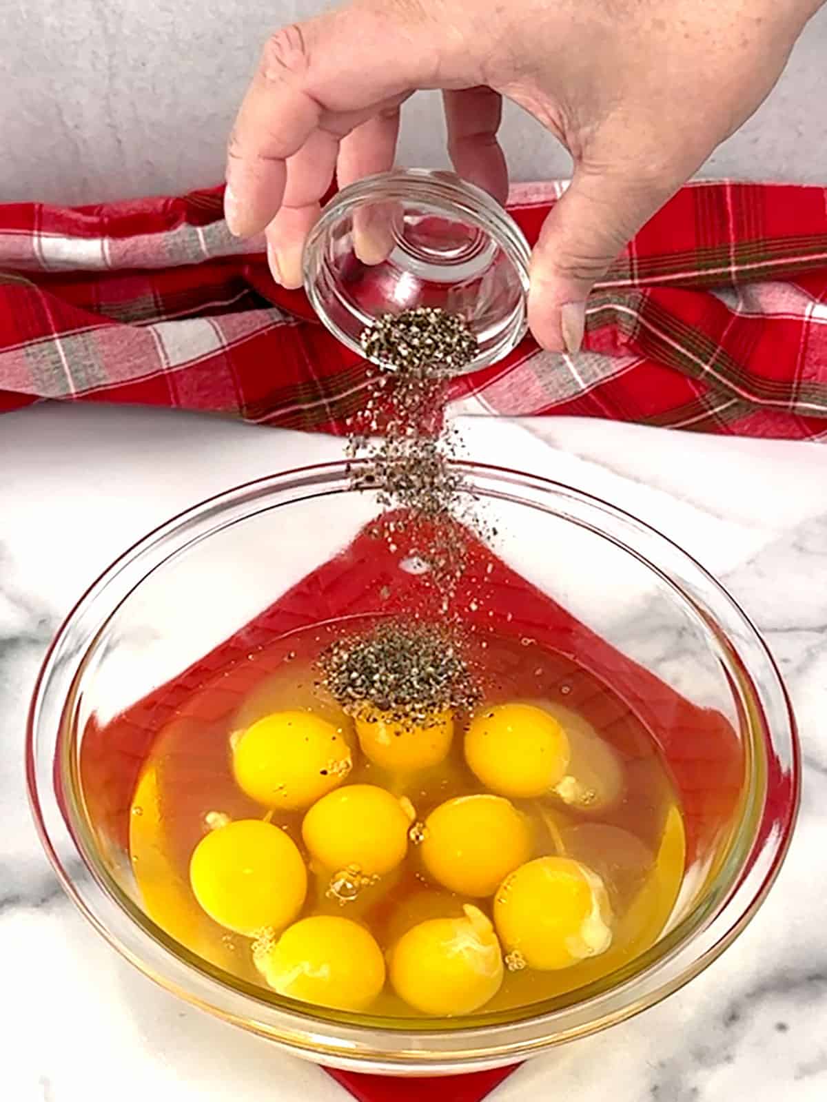 adding freshly ground pepper to eggs