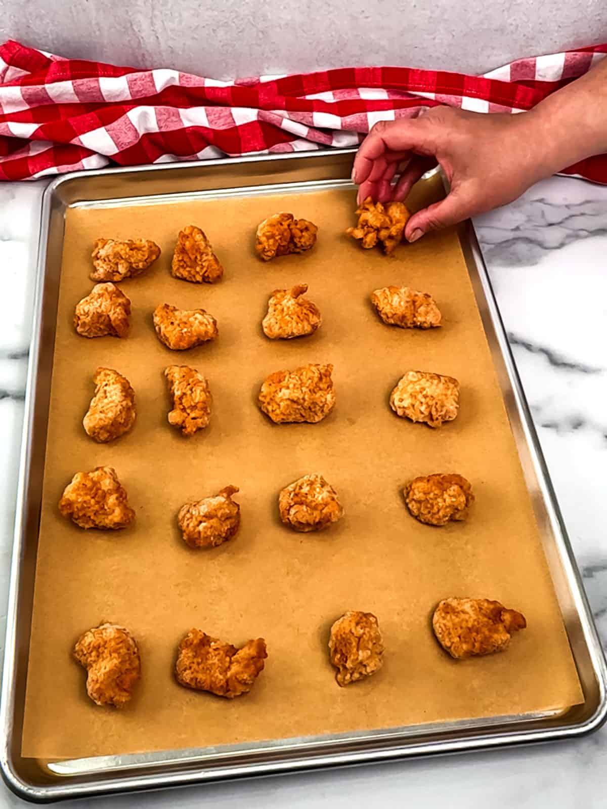 placing chicken nuggets on prepared pan