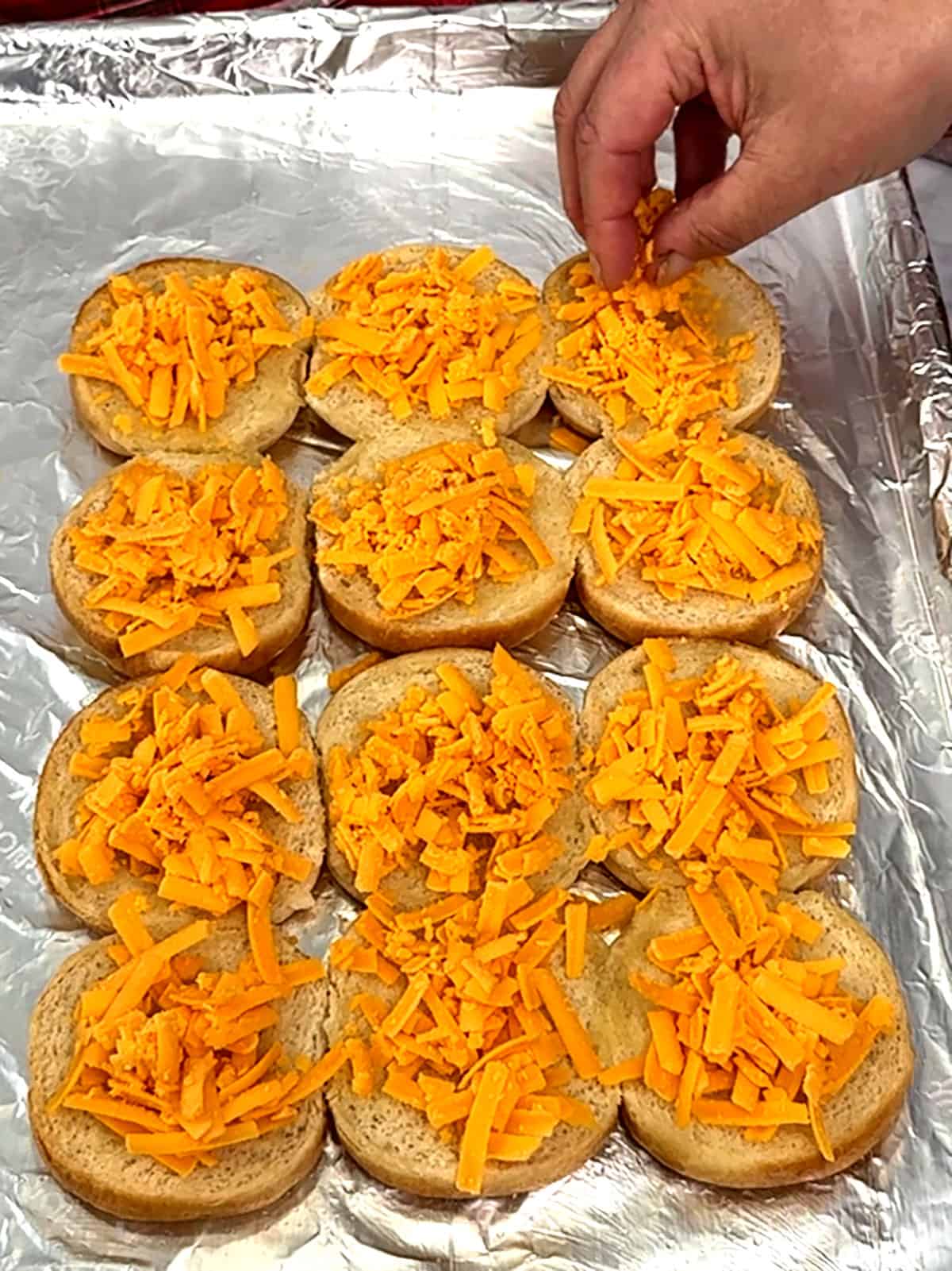 sprinkling cheese on bottom buns
