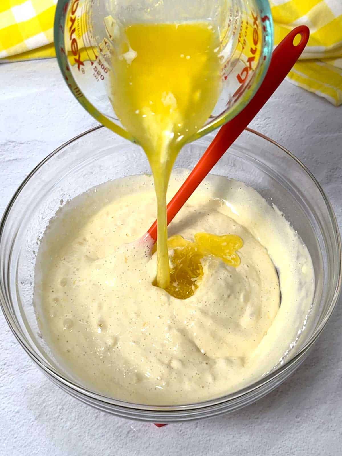 Adding melted butter to the madeleine batter.
