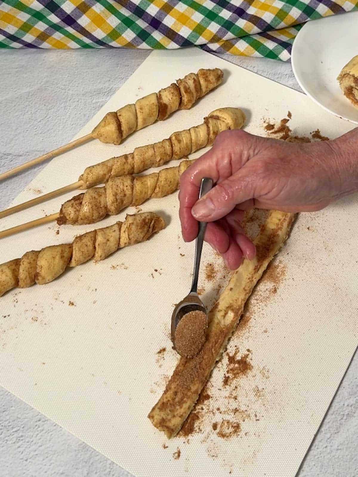 Adding cinnamon sugar to the strip of dough.
