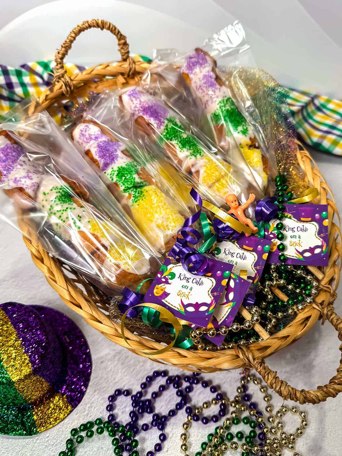 Packaged king cakes on a stick in a basket.